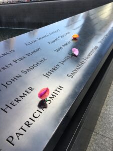 Close-up photos of names at the 9/11 Memorial, with flowers left on some names in remembrance.